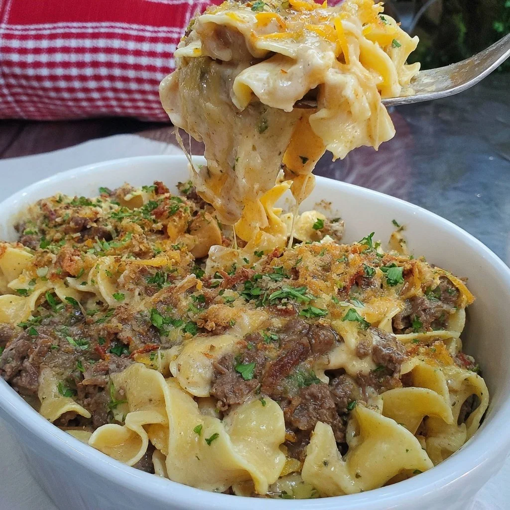 Sour Cream Beef Noodle Casserole topped with cheese in a baking dish