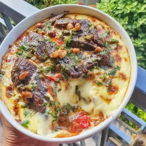 Creamy polenta casserole with braised beef and gremolata garnish on a serving plate