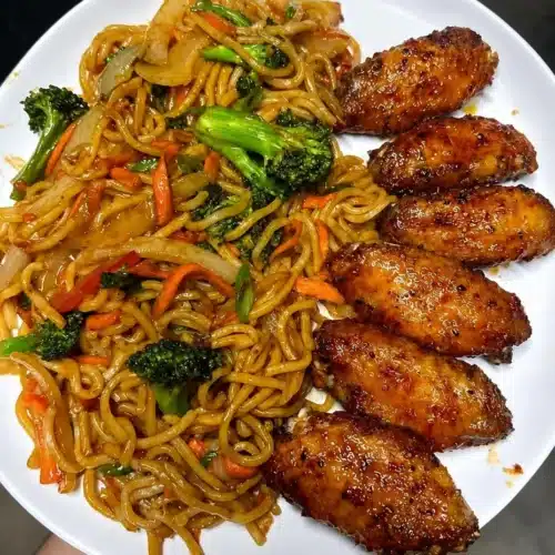 Delicious chicken wings served with stir-fry noodles, perfect for flavor lovers.