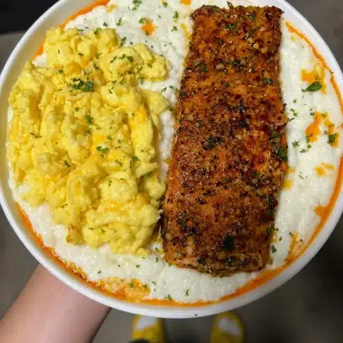 A delicious serving of salmon and cheesy eggs with grits on a plate