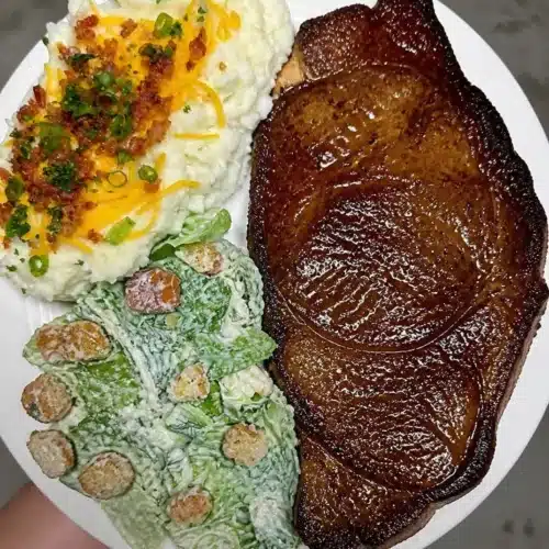 Delicious T-Bone steak served with loaded mashed potatoes and Caesar salad.